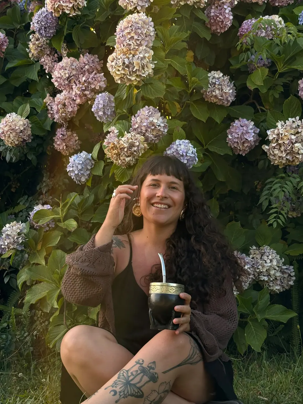 Agustina sentada frente a hortensias con un mate